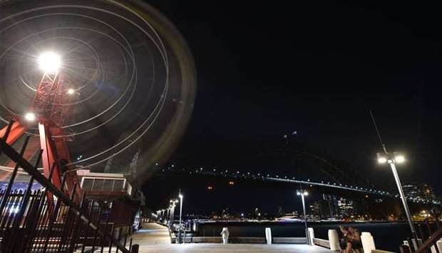The Sydney Harbour Bridge, the Opera House and the ferris wheel are seen after their lights went out as seen from Sydney's Luna Park for the Earth Hour environmental campaign