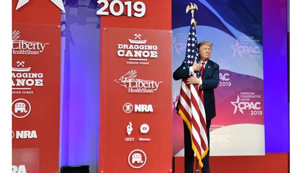 President Donald Trump hugs the US flag yesterday at the annual Conservative Political Action Conference in National Harbor, Maryland.