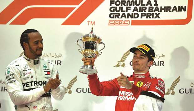 Race-winning Mercedes driver Lewis Hamilton (left) applauds as Ferrari driver Charles Leclerc lifts his third place trophy yesterday. (AFP)
