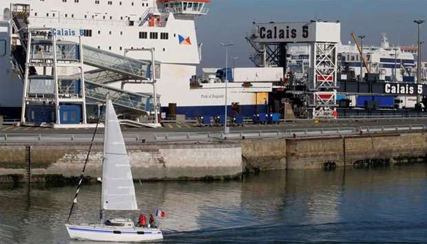 A sailboat glides past the ferry terminal as it leaves the port of Calais, France