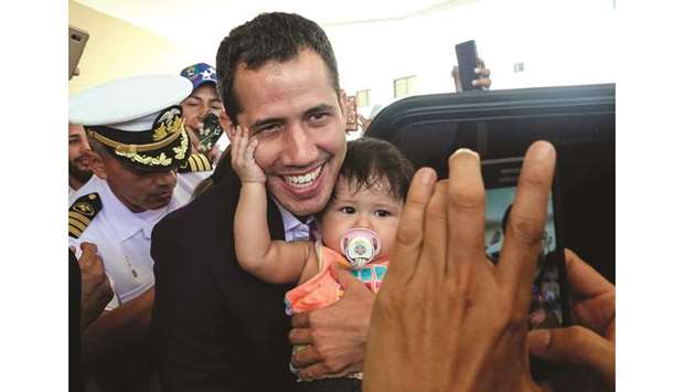 Venezuelan opposition leader and self-proclaimed acting president Juan Guaido poses for a picture with a baby before leaving his hotel in Salinas, Ecuador, yesterday.