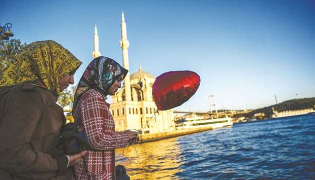 A woman holds a balloon as she goes about with her daily life near the Bosphorus bridge in the Ortakoy district in Istanbul (file). The government has set the goal to increase the share of Shariah-compliant banking assets to 15% of the countryu2019s total banking sector by 2025.