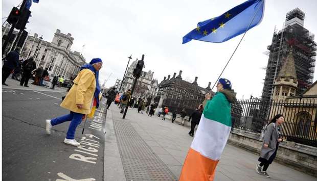 An anti-Brexit protester draped in an Irish tricolour flag and holding an EU flag stands outside of the Houses of Parliament in London, Britain