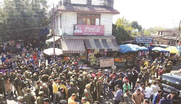 Policemen and onlookers stand at the site of a grenade blast in Jammu yesterday.