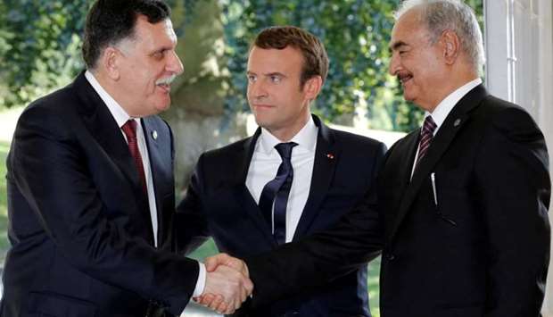 French President Emmanuel Macron stands between Libyan Prime Minister Fayez al-Serraj (L), and General Khalifa Haftar (R), commander in the Libyan National Army (LNA), who shake hands after talks over a political deal to help end Libyau2019s crisis in La Celle-Saint-Cloud near Paris, France, July 25, 2017.