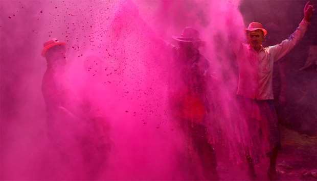 People dance as they throw coloured powder at each other during Holi celebrations in Kolkata