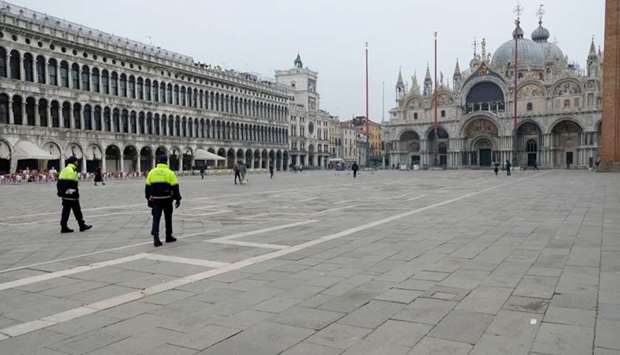 Police officers patrol a virtually deserted St. Mark's Square after a decree orders for the whole of Italy to be on lockdown in an unprecedented clampdown aimed at beating the coronavirus, in Venice