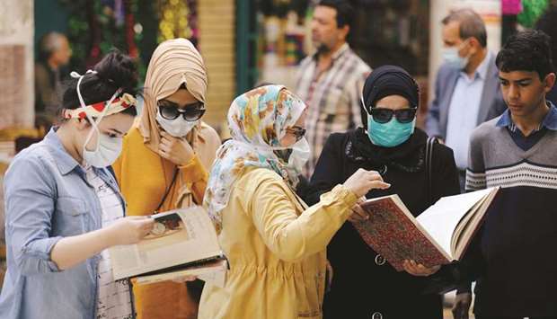 Iraqi women wear protective face masks, following an outbreak of coronavirus, as they look at books at Mutanabbi Street in Baghdad.