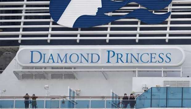 Masked passengers look on from on board the coronavirus-hit Diamond Princess cruise ship docked at Yokohama Port, south of Tokyo, Japan on February 20