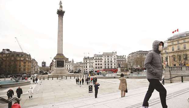 A man wearing a protective face mask walks through Trafalgar Square, as the number of coronavirus cases grow, in London yesterday.