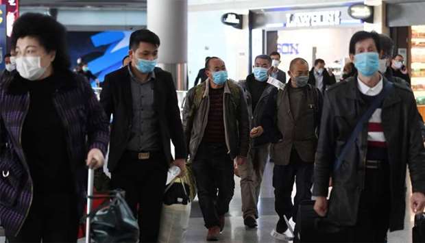 Passengers wear face masks as a preventive measure against the COVID-19 coronavirus as they arrive from an international flight at Beijing Capital Airport
