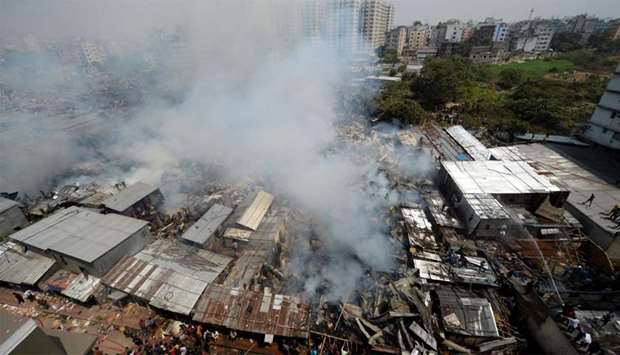 Smoke billows as firefighters work to extinguish a fire at a slum area in Dhaka