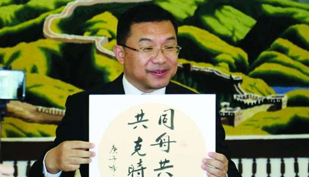 The ambassador displaying the Chinese saying that reads u201cSailing in the same boat, together we will overcome difficultiesu201d