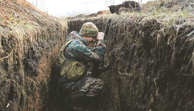 A cat looks down at a Ukrainian soldier resting in a trench on the front line with Russia-backed separatists near Krasnogorivka village, Donetsk region.