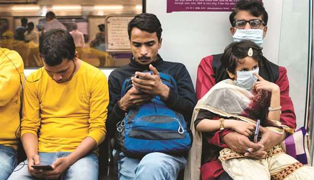 A man and his child wear facemasks as a preventive measure against the spread of the Covid-19 as they travel on the Delhi Metro in New Delhi yesterday.