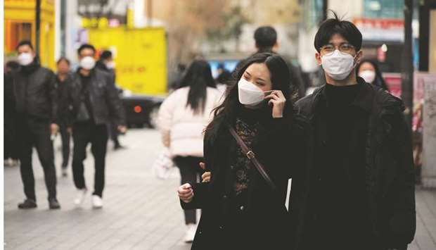 A couple wearing masks to prevent contracting the coronavirus walks in a shopping district in Seoul, South Korea, yesterday.