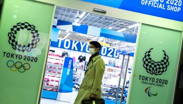 A man wearing a protective face mask, following an outbreak of the coronavirus disease (COVID-19), walks past a Tokyo Olympics 2020 souvenir shop in Tokyo, Japan