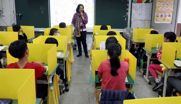 Pupils sit in desks with yellow dividers at Dajia Elementary school in Taipei
