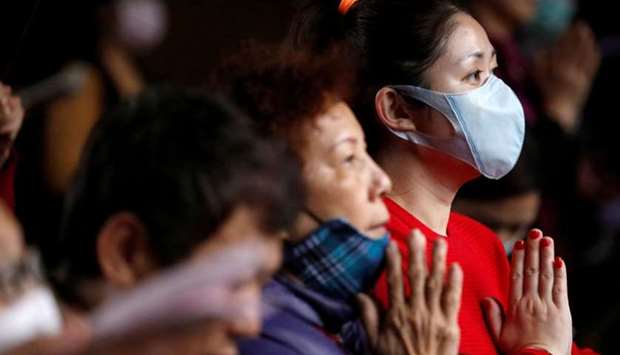 Devotees wear protective face masks, to protect themselves from the coronavirus (COVID-19), while praying at Lungshan Temple in Taipei, Taiwan