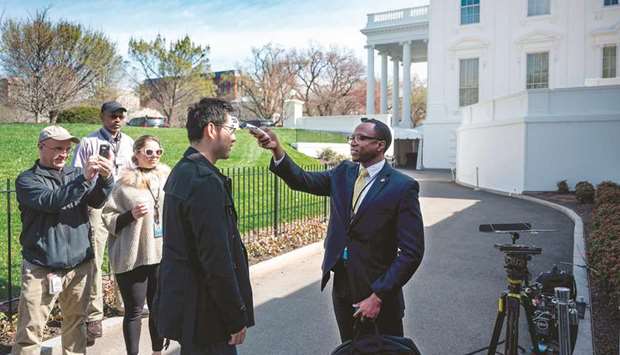 A doctor from the White House Physicians Office checks the temperature of a journalist outside the Brady Press Briefing Room prior to a press conference at the White House in Washington, DC.