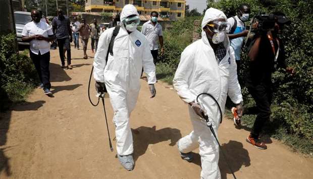 Kenyan health workers dressed in protective suits walk after disinfecting the residence where a coronavirus patient was staying, in the town of Rongai