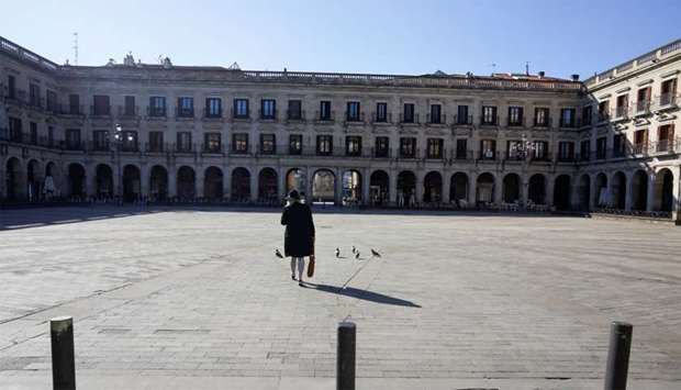A woman crosses a virtually deserted square, amidst concerns over Spain's coronavirus outbreak, in the Basque city of Vitoria, Spain