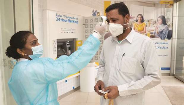 A bank client gets his temperature checked before entering a bank, following the outbreak of coronavirus, in Shaab, Kuwait, yesterday.