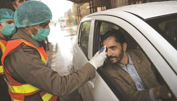 A health official of the Khyber Pakhtunkhwa emergency rescue service checks the temperature of a government employee before he is allowed to enter his office in Peshawar.