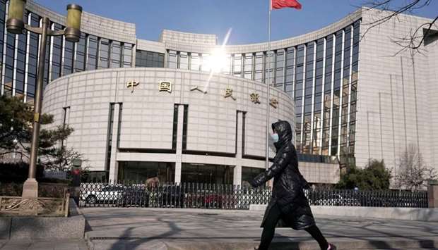 A woman wearing a mask walks past the headquarters of the People's Bank of China, the central bank, in Beijing, China, as the country is hit by an outbreak of the new coronavirus, February 3, 2020