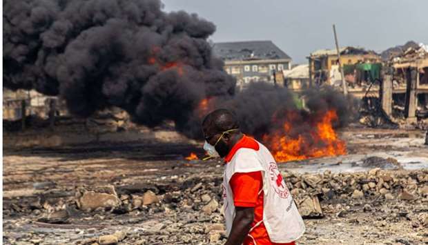 A member of the local Red Cross passes in front of a raging fire at the scene of a gas explosion yesterday in Lagos