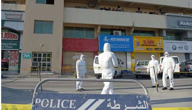 Bahraini policemen seal off a building housing foreign workers in the Salmabad industrial area as a precautionary measure after a resident tested positive for coronavirus (COVID-19), on the outskirts of the capital Manama on March 13.