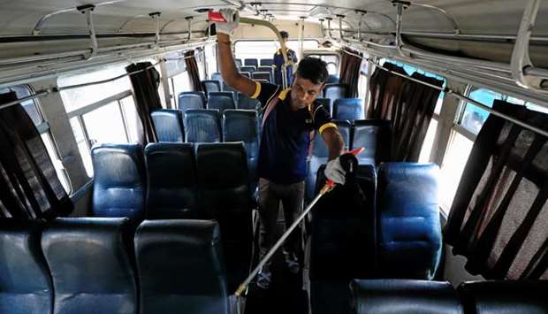 A worker sprays disinfectant inside a bus at a private bus station, as the number of people tested positive for coronavirus (COVID-19) in the country increases to 18, in Colombo, Sri Lanka