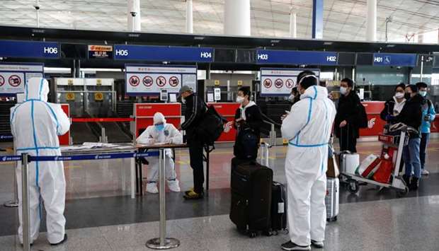Staff members wearing protective suits register passengers in front of a check-in counter of Air China at Beijing Capital International Airport as the country is hit by an outbreak of the novel coronavirus, in Beijing, China