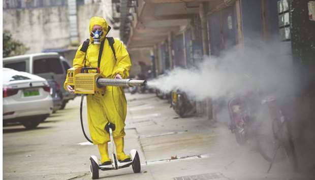 A medical staff member sprays disinfectant at a residential area in Wuhan. the Covid-19 outbreak, which started when a new coronavirus leapt from an animal to a human in China, now threatens to disrupt economic and social life around the world.