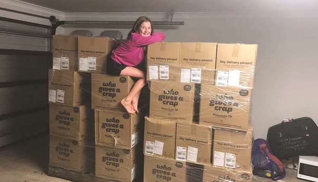A girl sits on top of boxes containing toilet paper in Toowoomba, Australia, in this picture obtained from social media.  When people lay in a six-month supply of toilet paper they leave other people scrambling to find it.