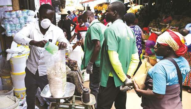 A trader wearing a protective mask weighs grains at the Kimironko market as shoppers stock up on essential items that have been price fixed in order to prevent exploitative practices in Kigali, Rwanda yesterday.