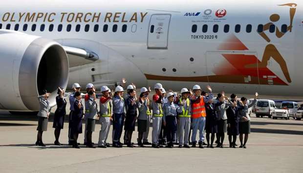 Staff members of Japan Airlines and All Nippon Airways and runway crew wave as they see off the 'Tokyo 2020 Go' aircraft, before it departs for Greece, to transport the Olympic Flame back to Japan, at Haneda international airport in Tokyo, Japan.