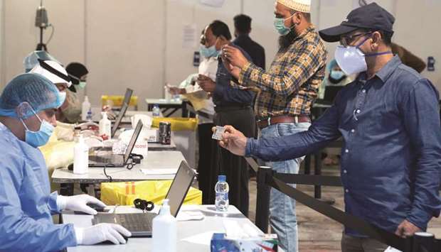 Expatriates, arriving to Kuwait, stand a safe distance apart to give their details to ministry of health officials in a makeshift coronavirus testing centre, at Kuwait International Fairgrounds in Mishref, yesterday.