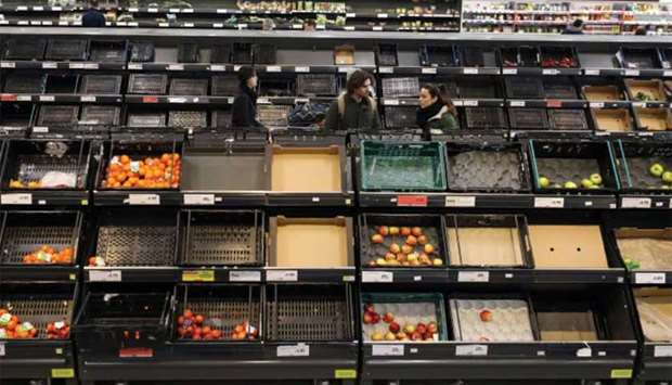 People walk past empty shelves at the fruit and vegetable aisle of a Sainsburyu2019s supermarket in Fulham, London, yesterday.