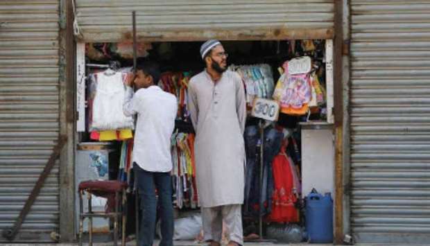 Shopkeepers stand outside their partially opened shop as police officers try to close market after Sindh provincial government decided to shut markets, restaurants, beaches and discouraged large gatherings amid the outbreak of novel coronavirus, in Karachi, Pakistan.