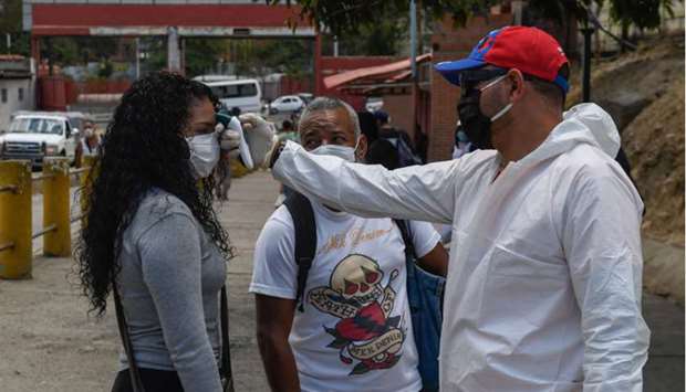 Health workers check peopleu2019s temperature in Caracas (left) and the Panamiam town of Cuango.