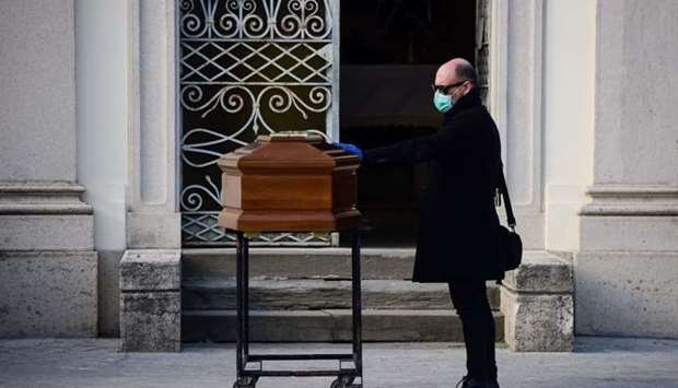 A man touches the coffin of his mother during a funeral service in the closed cemetery of Seriate, near Bergamo, Lombardy