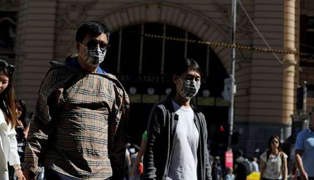 People wearing face masks walk by Flinders Street Station after cases of the coronavirus were confirmed in Melbourne, Victoria, Australia, January 29, 2020.