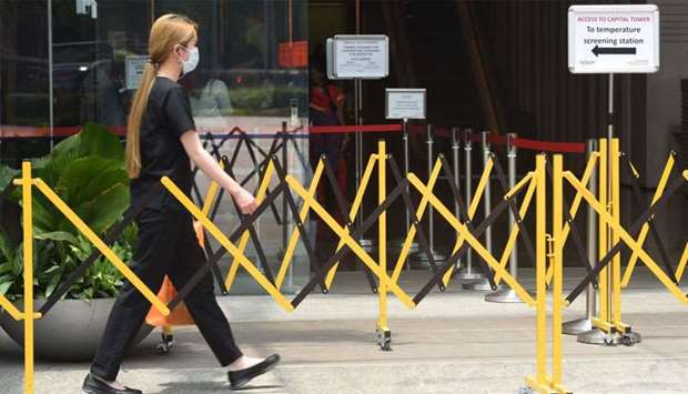 A woman wearing a face mask approaches a temperature screening area of an office building as a preventive measure against the COVID-19 coronavirus in Singapore