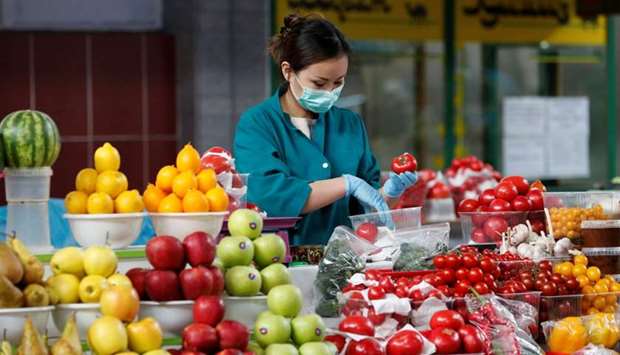 A vendor wearing a protective face mask following an outbreak of the coronavirus disease (COVID-19) pack vegetables at a local food market, also known as bazaar, in Almaty, Kazakhstan