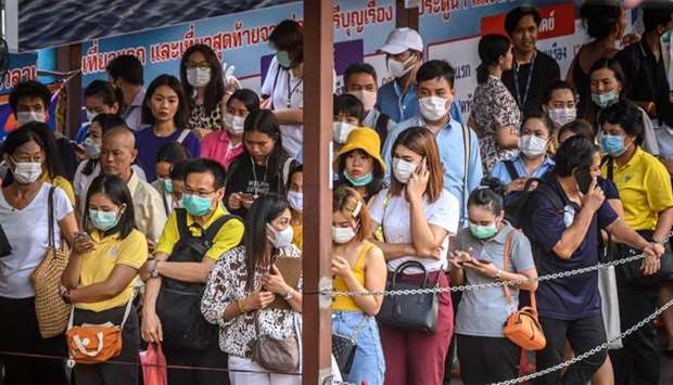 Commuters, wearing facemasks amid fears of the spread of the COVID-19 novel coronavirus, wait for a canal boat in Bangkok