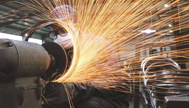 A worker wearing a face mask works on a production line manufacturing bicycle steel rim at a factory in Hangzhou, Zhejiang province.