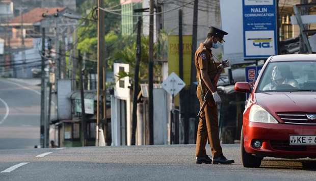 A police man speaks to a car driver at a checkpoint on an empty street after authorities announced a weekend curfew as a preventive measure against the spread of the Covid-19 novel coronavirus, in Colombo yesterday.