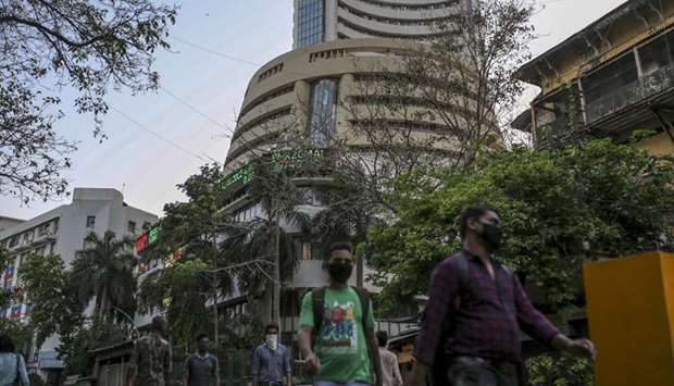 Pedestrians wearing protective masks walk past the Bombay Stock Exchange building in Mumbai. The Sensex tumbled 13% to 25,981.24 points at the close in Mumbai yesterday, its biggest one-day drop ever since data going back to 1979,  while the NSE Nifty 50 Index sank by a similar amount.