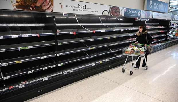 A shopper walks past empty food shelves amidst the novel coronavirus Covid-19 pandemic, in Manchester, northern England. If we continue to strip supermarket shelves bare others are deprived of essential products.